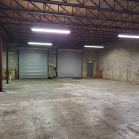 Warehouse interior with fluorescent lights, concrete floors, and loading docks