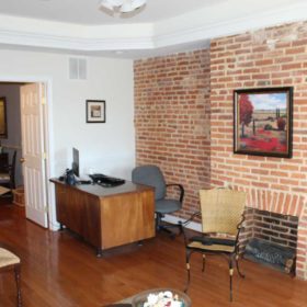 Second story office interior showing desk and brick fireplace