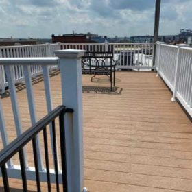Spacious rooftop deck with white wooden fencing and seating area