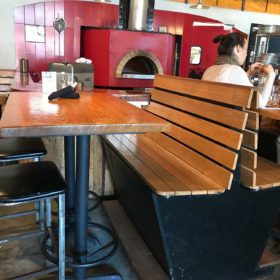 Wooden table and bench in front of red pizza oven